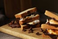 Delicious marshmallow sandwiches with bread and chocolate on wooden board, closeup