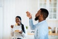 Delicious Meal. Hungry African American Man Slurping Long Spaghetti In Kitchen