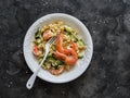 Delicious mediterranean lunch - creamy orzotto with shrimp and zucchini on a dark background, top view