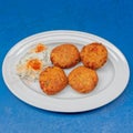 Delicious minced tomato fries with tzatziki sauce, a gourmet Greek plate on blue table surface. Royalty Free Stock Photo