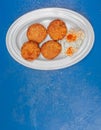 Delicious minced tomato fries with tzatziki sauce, a gourmet Greek plate on blue table surface. Royalty Free Stock Photo