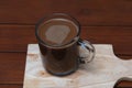 Delicious mocha flavored coffee in a cup on a wooden cutting board.