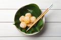 Delicious mochi served in bowl with green leaf and chopsticks on white wooden table, top view. Traditional Japanese dessert Royalty Free Stock Photo