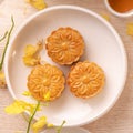 Delicious moon cake for Mid-Autumn festival with beautiful pattern, decorated with yellow flowers and tea. Concept of festive