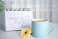 Delicious morning coffee, flower and HAVE A NICE DAY wish on white table indoors