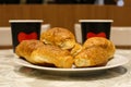 Delicious morning coffee for two: fresh buns on the background of paper cups on a table in a cafe, close-up Royalty Free Stock Photo