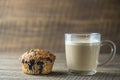 Delicious muffin with blueberries and cappuccino glass cup on a wooden table, closeup. Fresh cupcake and coffee for breakfast Royalty Free Stock Photo