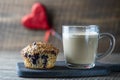 Delicious muffin with blueberries and cappuccino glass cup on a wooden table, closeup. Fresh cupcake and coffee for breakfast