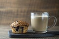 Delicious muffin with blueberries and cappuccino glass cup on a wooden table, closeup. Fresh cupcake and coffee for breakfast Royalty Free Stock Photo