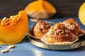 Delicious muffins with sunflower seeds and cut pumpkin on color table Royalty Free Stock Photo