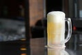 Delicious mug of super cold and refreshing draft beer on the table in the blurred background Royalty Free Stock Photo