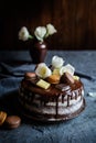 Naked cake filled with mascarpone cream, topped with chocolate and decorated with flowers, macarons and chocolate pieces Royalty Free Stock Photo