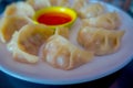 Delicious Nepali traditional snack, chicken MoMo serve with spicy and sour sauce in a white plate