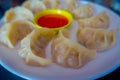 Delicious Nepali traditional snack, chicken MoMo serve with spicy and sour sauce in a white plate