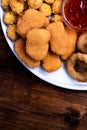 Snacks for beer on a white plate are: chicken nuggets, onion rings in tempura, chicken popcorn and chili sauce Royalty Free Stock Photo