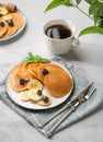 Delicious oat banana pancakes with fresh fruit slices, berries, mint and honey on a light background with a cup of black coffee Royalty Free Stock Photo