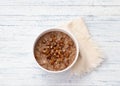 Delicious oatmeal in a white bowl, dates fruits and cocoa. healthy breakfast on light blue background