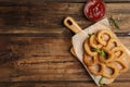 Delicious onion rings and ketchup on wooden table, flat lay. Space for text Royalty Free Stock Photo