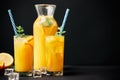 Delicious orange juice with ice, mint and fresh fruits on black table background with copy space Royalty Free Stock Photo