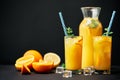 Delicious orange juice with ice, mint and fresh fruits on black table background with copy space Royalty Free Stock Photo