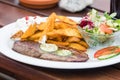 delicious ostrich steak with potato wedges and salad