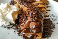 Delicious pancake crepe filled with chocolate and chocolate topping and crumbs and whipped cream as tasty dessert cheat caloric Royalty Free Stock Photo