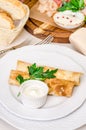 Delicious pancake with salty salmon, fresh green herbs and white cheese on plate, banquet restaurant table with dishes, snack, Royalty Free Stock Photo