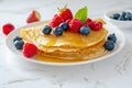 Delicious pancakes with berries, honey or maple syrup. Homemade pancakes and sweet syrup on white plate isolated. Royalty Free Stock Photo