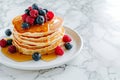 Delicious pancakes with berries, honey or maple syrup. Homemade pancakes and sweet syrup on white plate isolated. Royalty Free Stock Photo