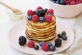 Delicious pancakes with berries and honey on a pink plate, side view. Royalty Free Stock Photo