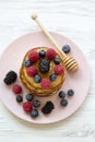 Delicious pancakes with berries and honey on a pink plate, top view. Royalty Free Stock Photo