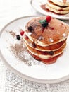 Delicious pancakes with syrup and berries on stylish plate on rustic table. Yummy homemade breakfast. Stack of pancakes with jam