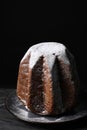 Delicious Pandoro cake decorated with powdered sugar on dark table. Traditional Italian pastry