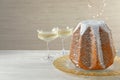 Delicious Pandoro cake decorated with powdered sugar and sparkling wine on white wooden table, space for text. Traditional Italian Royalty Free Stock Photo