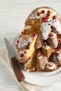 Delicious Pandoro Christmas tree cake with powdered sugar and berries on white wooden table, closeup