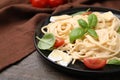 Delicious pasta with brie cheese, tomatoes and basil leaves on wooden table, closeup. Space for text Royalty Free Stock Photo