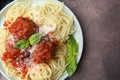Delicious pasta with meatballs, basil and cheese on brown textured table, top view. Space for text Royalty Free Stock Photo