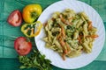 Delicious pasta with vegetables and cheese on a white plate green wooden background Royalty Free Stock Photo