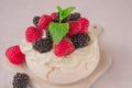 Delicious Pavlova meringue cake decorated with whipped cream, fresh blackberries, raspberries and mint.