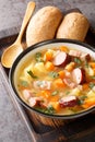 Delicious pea soup with vegetables, bacon and sausages close-up in a bowl. Vertical Royalty Free Stock Photo