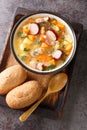 Delicious pea soup with vegetables, bacon and sausages close-up in a bowl. Vertical top view Royalty Free Stock Photo