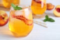 Delicious peach lemonade made with soda water on white wooden table, closeup. Space for text