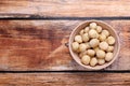 Delicious peeled Macadamia nuts in bowl on wooden table, top view. Space for text Royalty Free Stock Photo