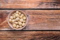 Delicious peeled Macadamia nuts in bowl on wooden table, top view. Space for text Royalty Free Stock Photo