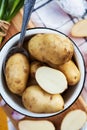 Delicious photo of washed raw potatoes in a plate on a wooden Board, against the background of green onions, large salt