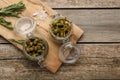 Delicious pickled capers and rosemary twigs on wooden table, top view. Space for text Royalty Free Stock Photo