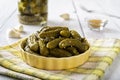 Delicious pickled cornichons in a yellow ceramic bowl over checkered napkin on a table. Whole green gherkins marinated with dill Royalty Free Stock Photo