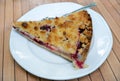 Delicious piece of cake with berry cherry and raspberry, with caramel on a white plate on wooden table.