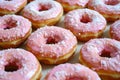 Delicious pink-frosted donuts with colorful sprinkles arranged on a wooden board. These tasty treats are perfect for