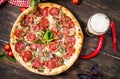 Delicious pizza, glass of beer vegetables and spices on wooden table. Royalty Free Stock Photo